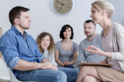 man sitting in group therapy and listening to the psychologist